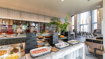 A buffet area with various food options, a chef preparing food, and a seating area with tables and chairs.