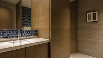 A modern bathroom with a wooden vanity, a sink, and a shower area.