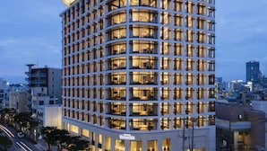 Un hôtel moderne à la façade incurvée, doté de plusieurs étages et de fenêtres illuminées.