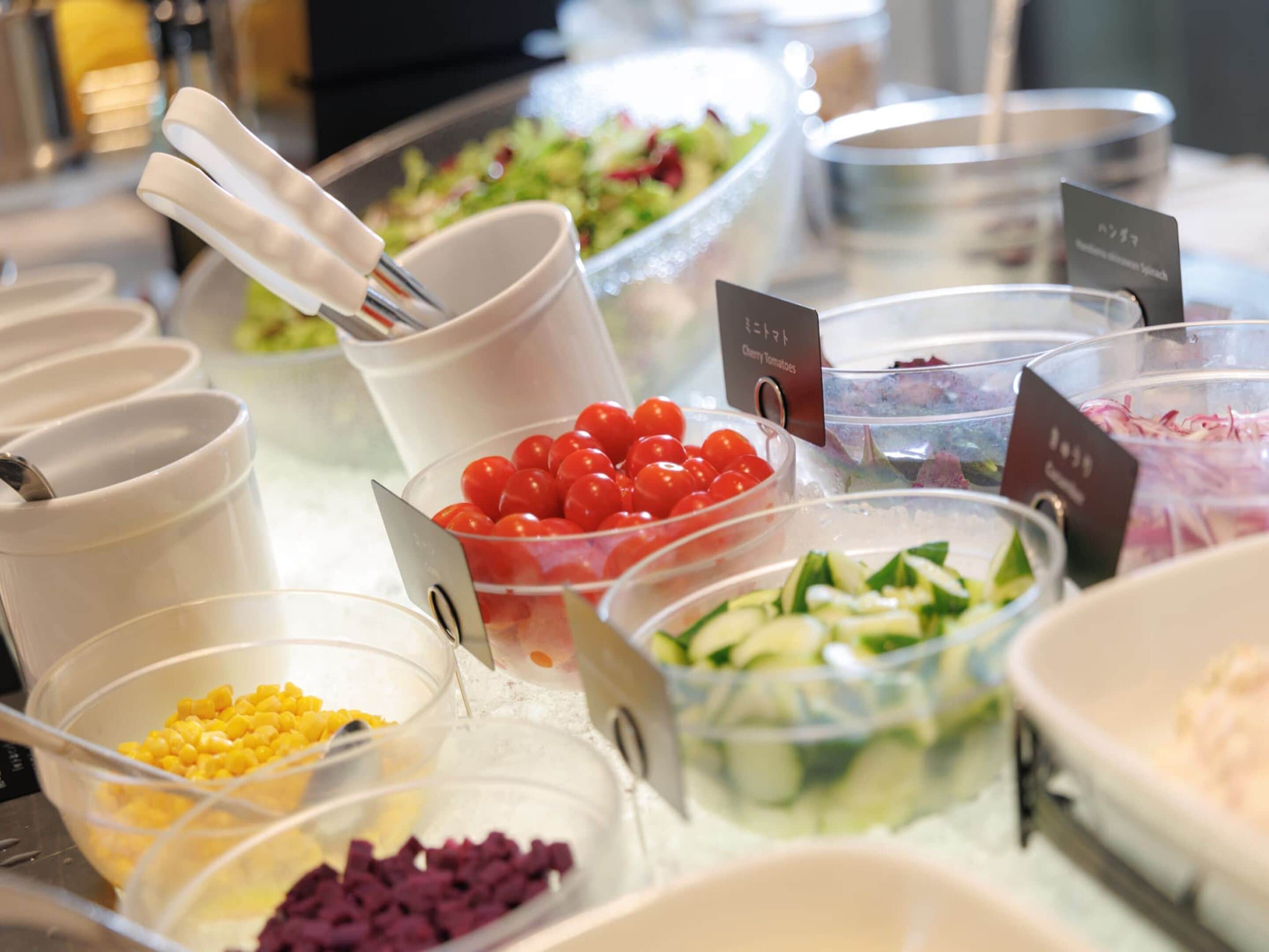 Ein Buffet mit verschiedenen Speisen, darunter Kirschtomaten, Mais und Salat.