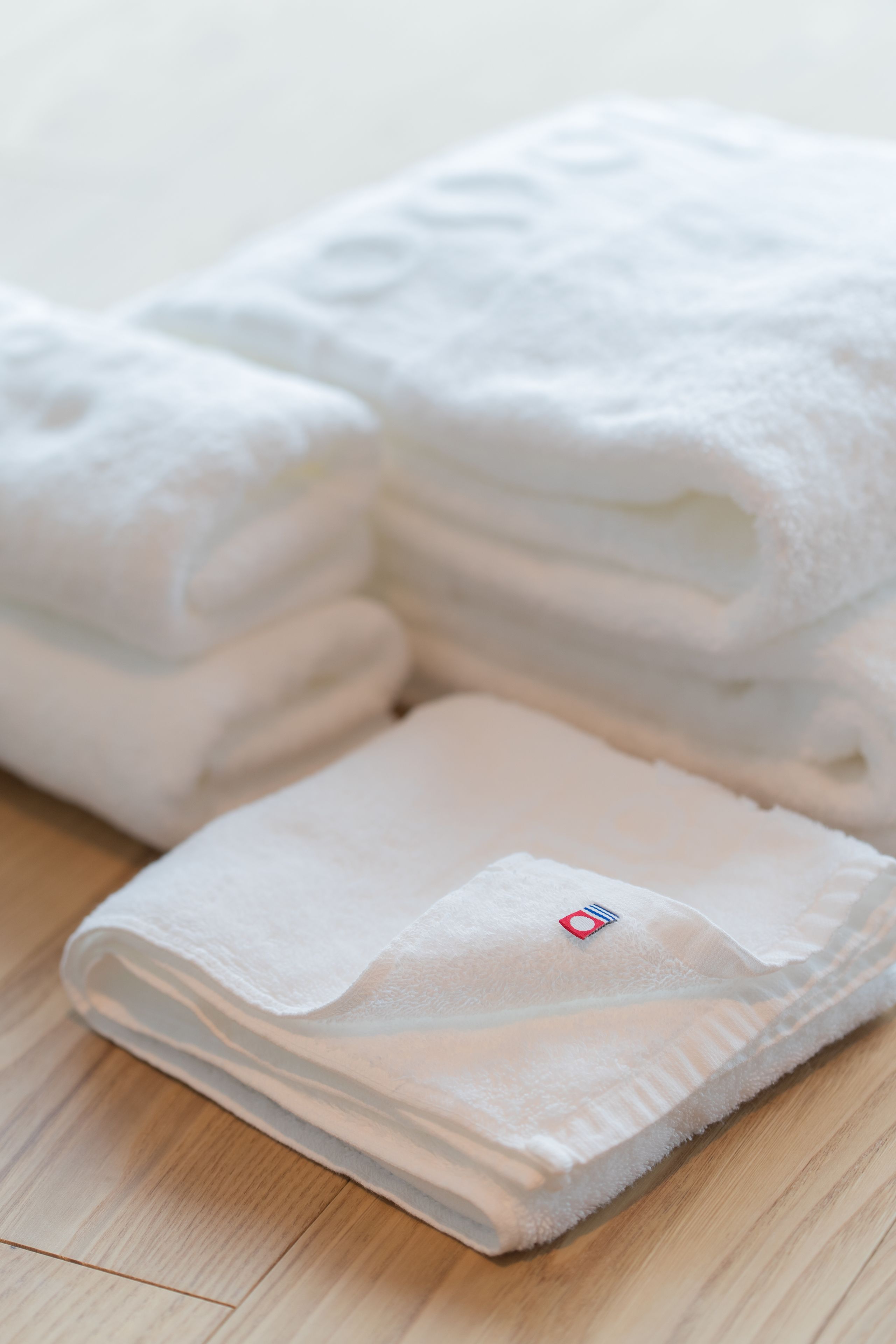 A stack of neatly folded white towels on a wooden floor.