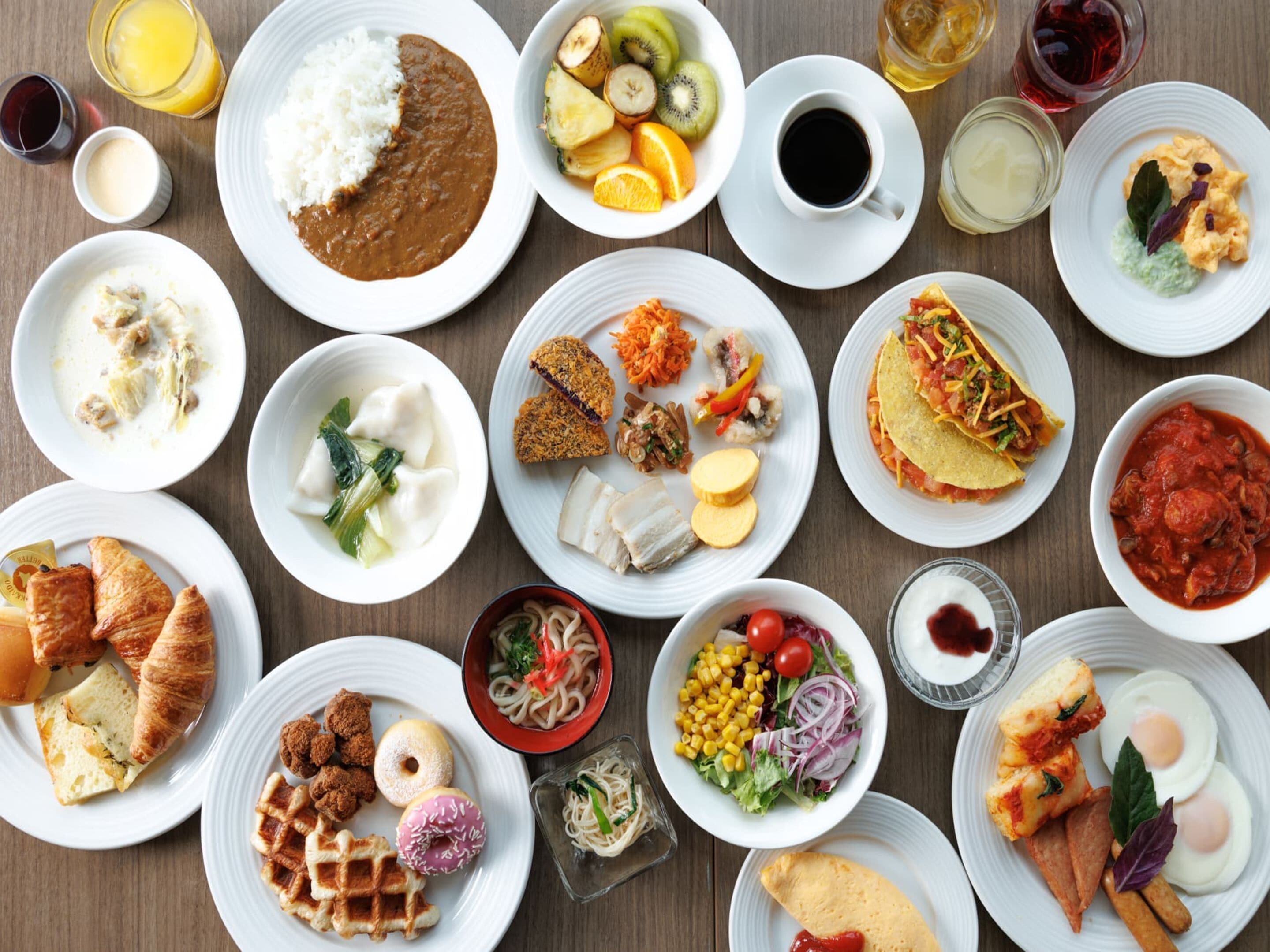 A variety of dishes including rice, soup, and pastries on a wooden table.