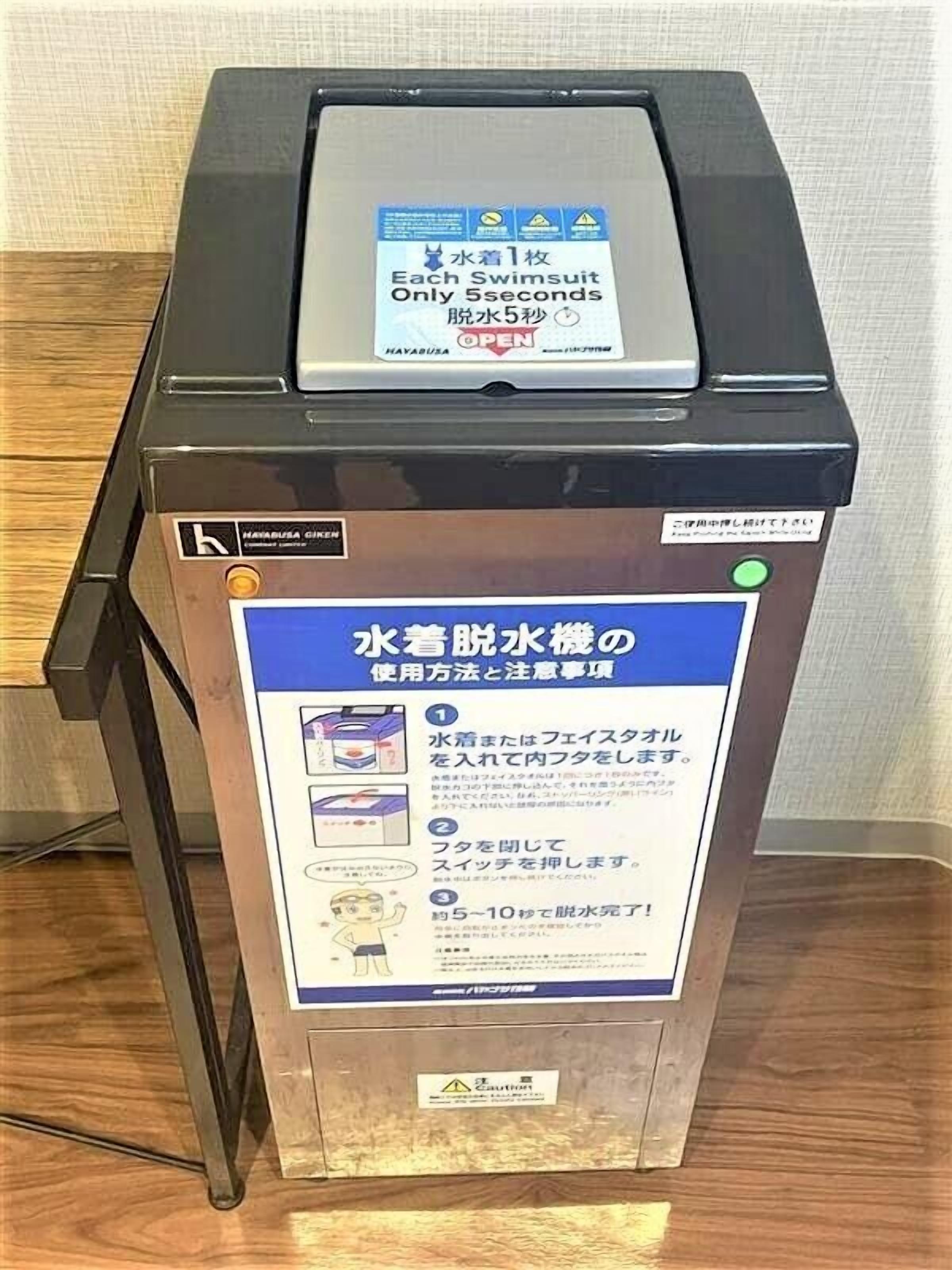 Un kiosque en libre-service avec des instructions en japonais, un terminal de paiement et un bouton vert.