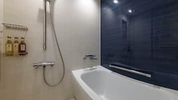 A modern bathroom with a white bathtub, a shower with a handheld showerhead, and a dark tiled wall.
