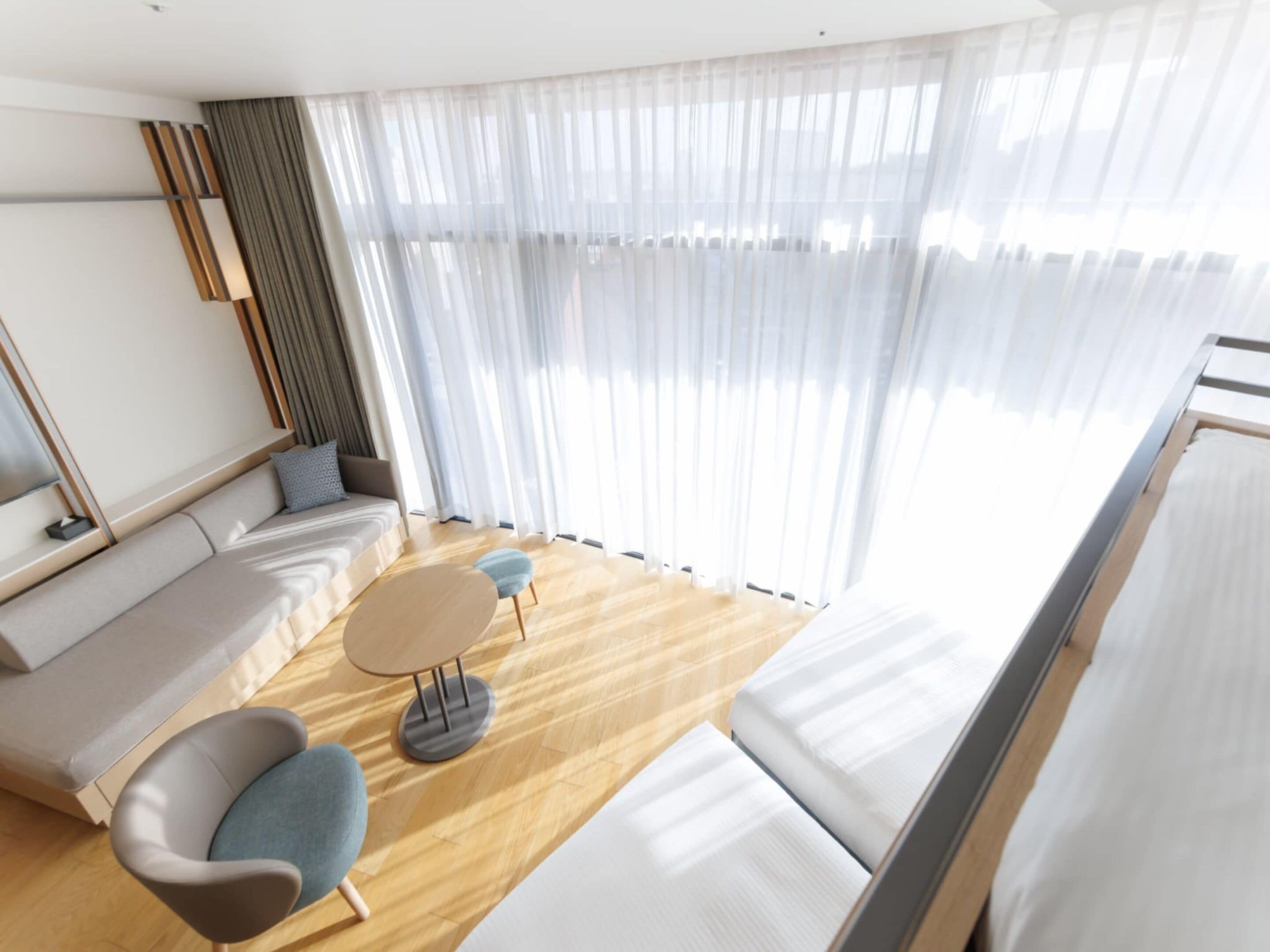A modern living room with a sofa, chairs, a small round table, and a large window with sheer curtains.