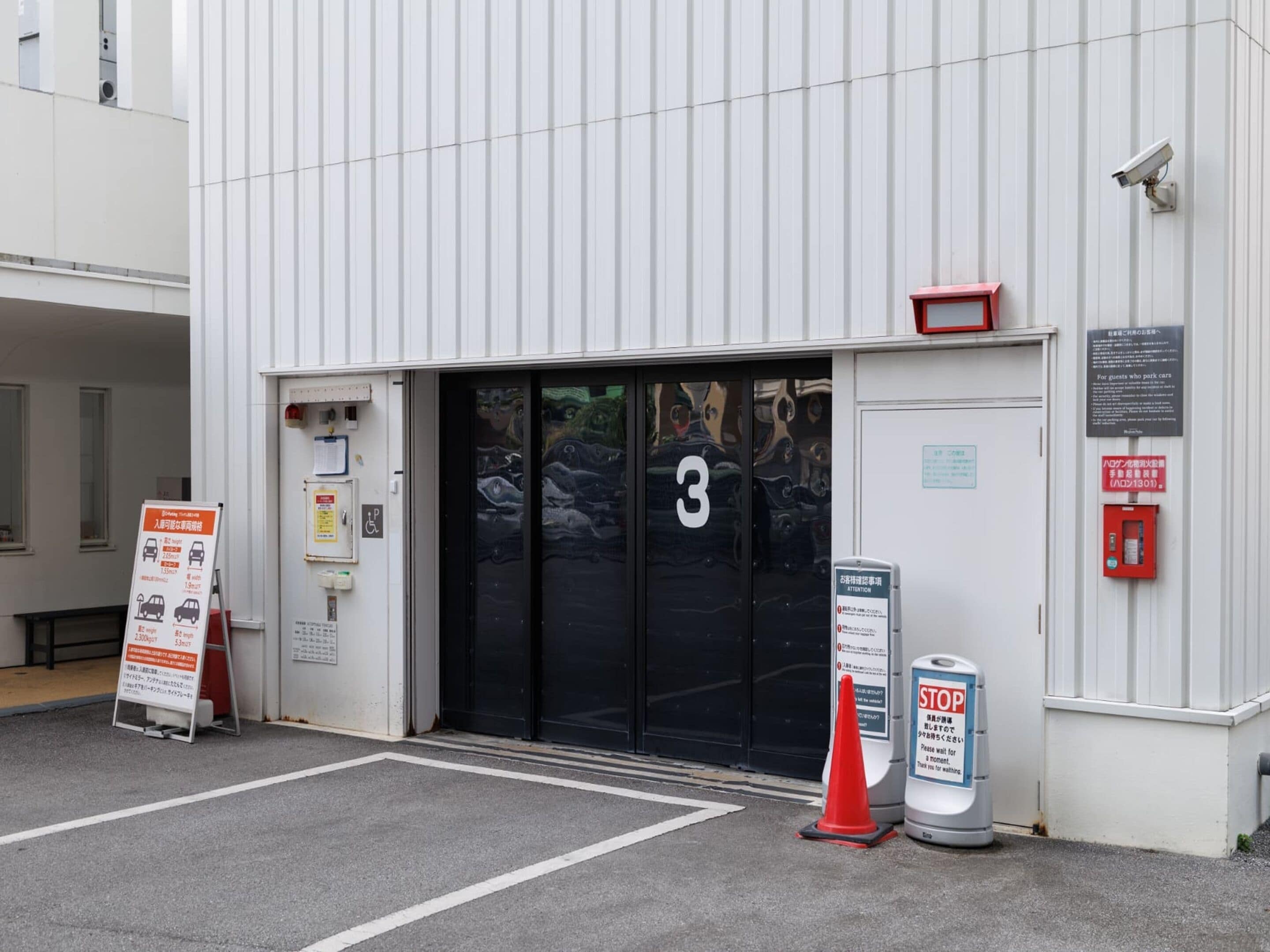 A building entrance with a number 3 sign, a stop sign, and a wheelchair accessibility sign.