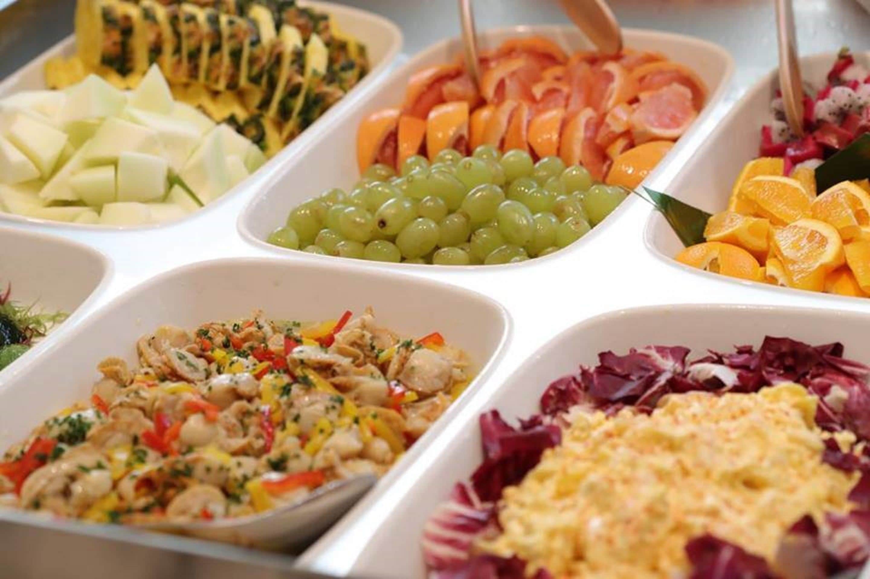 A buffet with various food options including fruits, vegetables, and a salad.