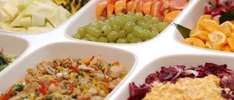 A buffet with various food options including fruits, vegetables, and a salad.