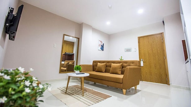 A modern living room with a sofa, a coffee table, a mirror, and a door. - GK Garden Apartment (Ho Chi Minh City)