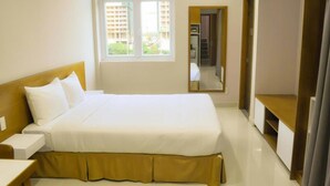 A hotel room with a large bed, a bedside table, a window with a view of buildings, and a mirror. - GK Garden Apartment (Ho Chi Minh City)