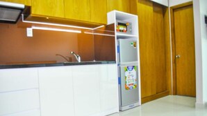 A kitchen with white cabinets, a stainless steel countertop, a built-in oven, and a refrigerator with a children's play area on top. - GK Garden Apartment (Ho Chi Minh City)