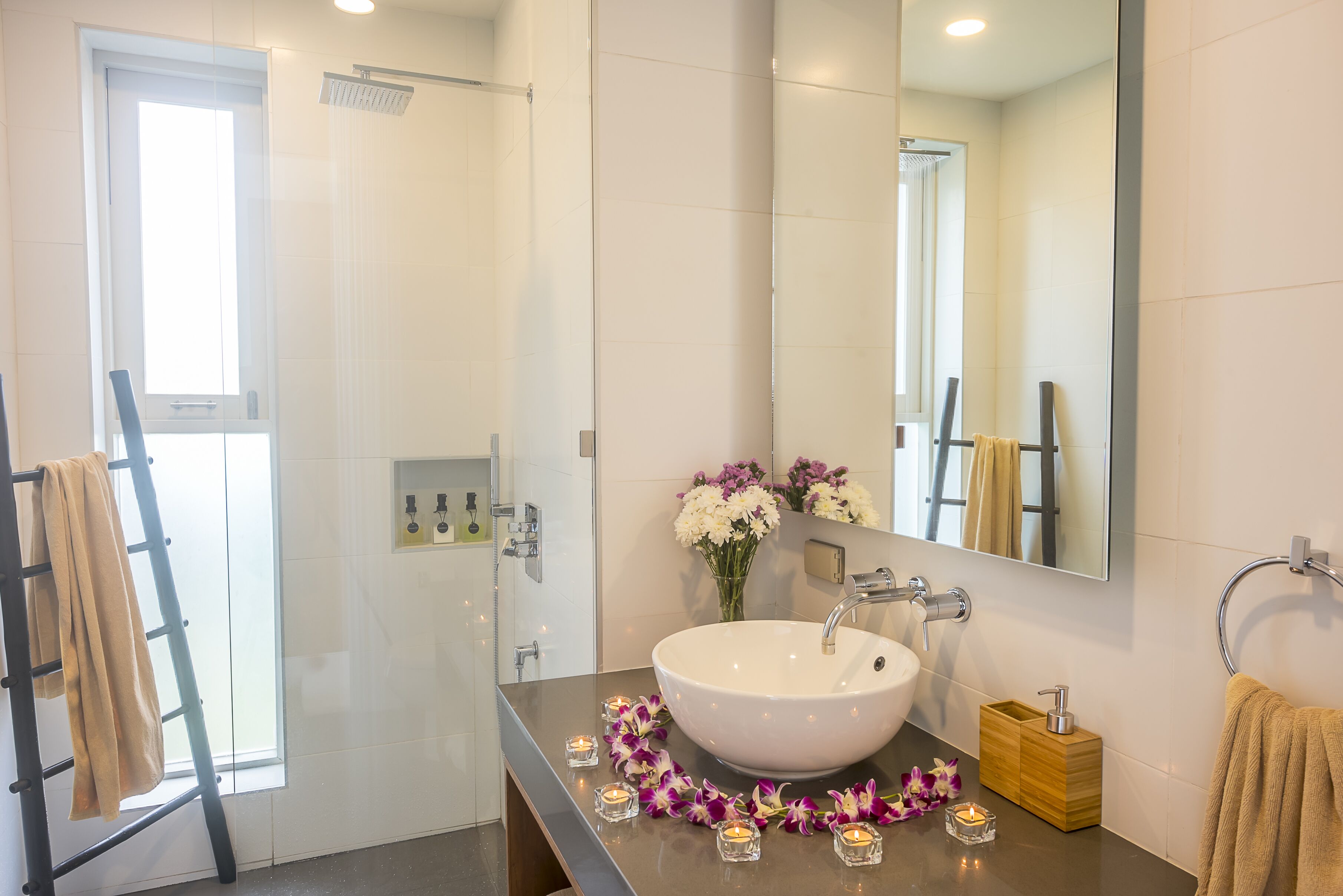 Un baño moderno con un lavabo grande, espejo y zona de ducha.