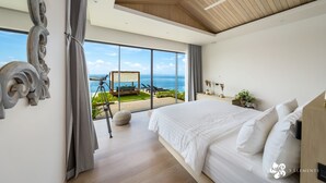A modern bedroom with a large bed, a ceiling fan, and a view of the ocean. - Bay Villas Koh Phangan (Ko Pha-ngan)