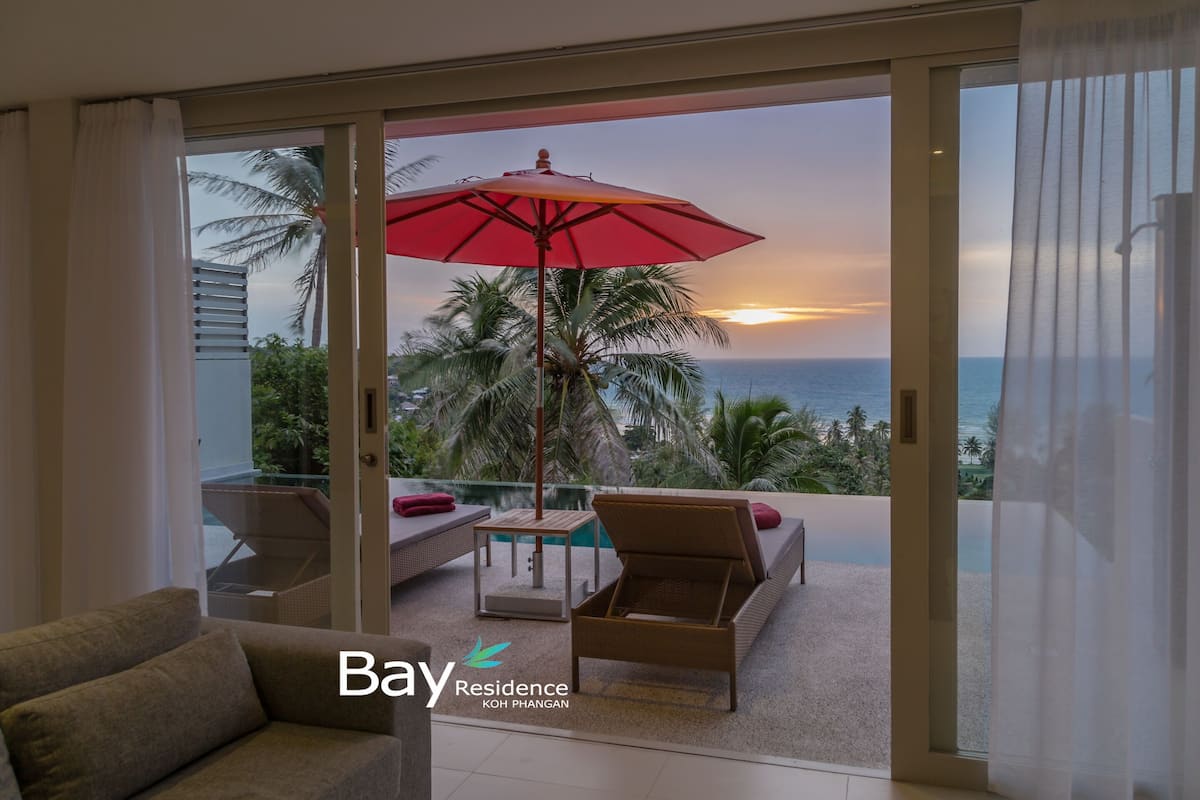 Un balcon avec un parasol rouge, un canapé et une table.