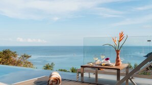 A sun lounger with a towel, a table with a vase and glasses, and a view of the ocean. - Bay Villas Koh Phangan (Ko Pha-ngan)