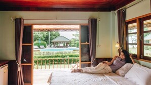 Une chambre avec un lit, une vue sur une piscine et un plafond en bois.