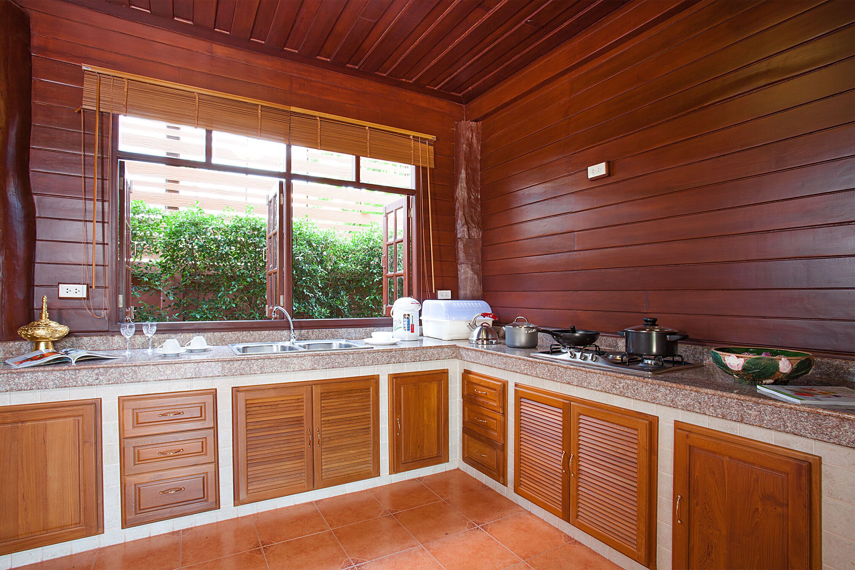 A kitchen with wooden cabinets, a granite countertop, and a window with blinds.