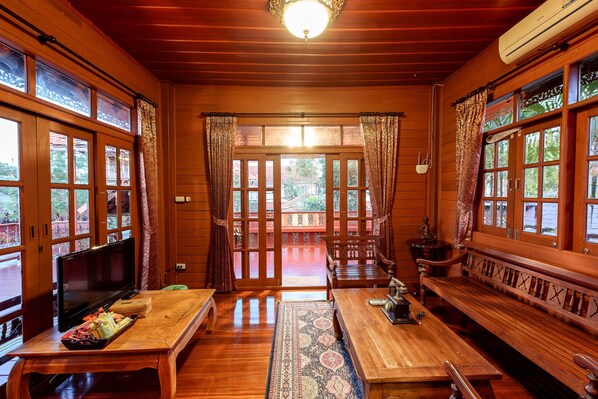 A wooden room with a television, a table with a tray of snacks, a bench, and a patterned rug.