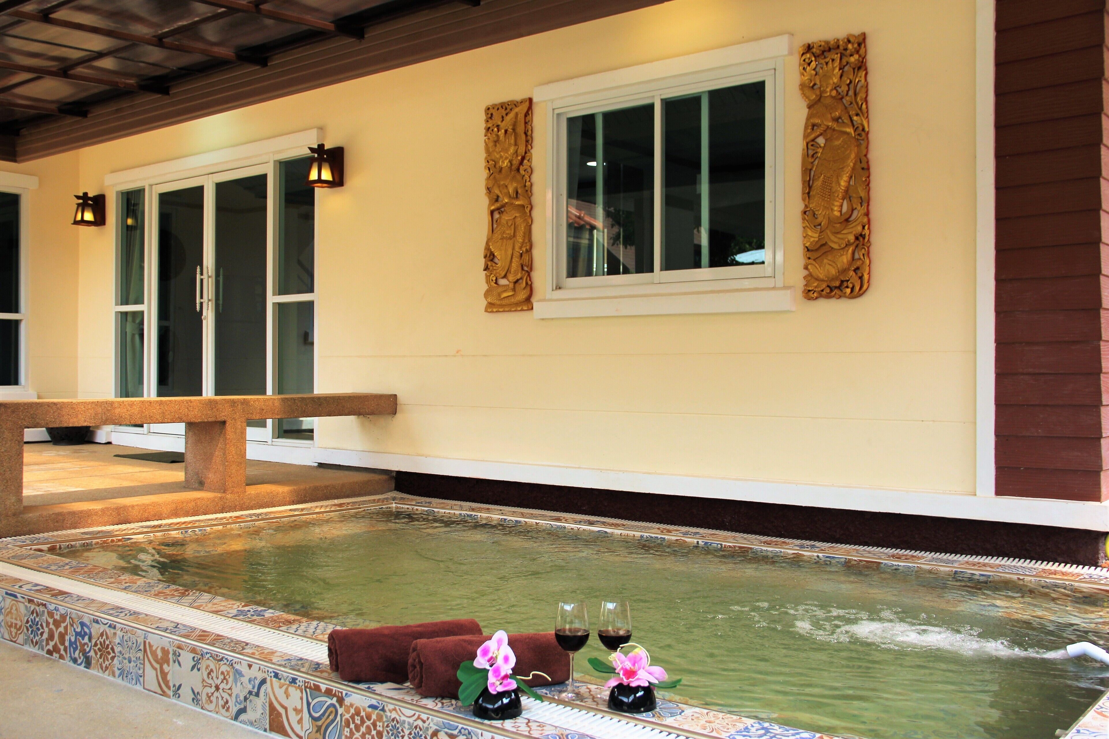 A spa area with a hot tub, two windows with decorative frames, and a bench.