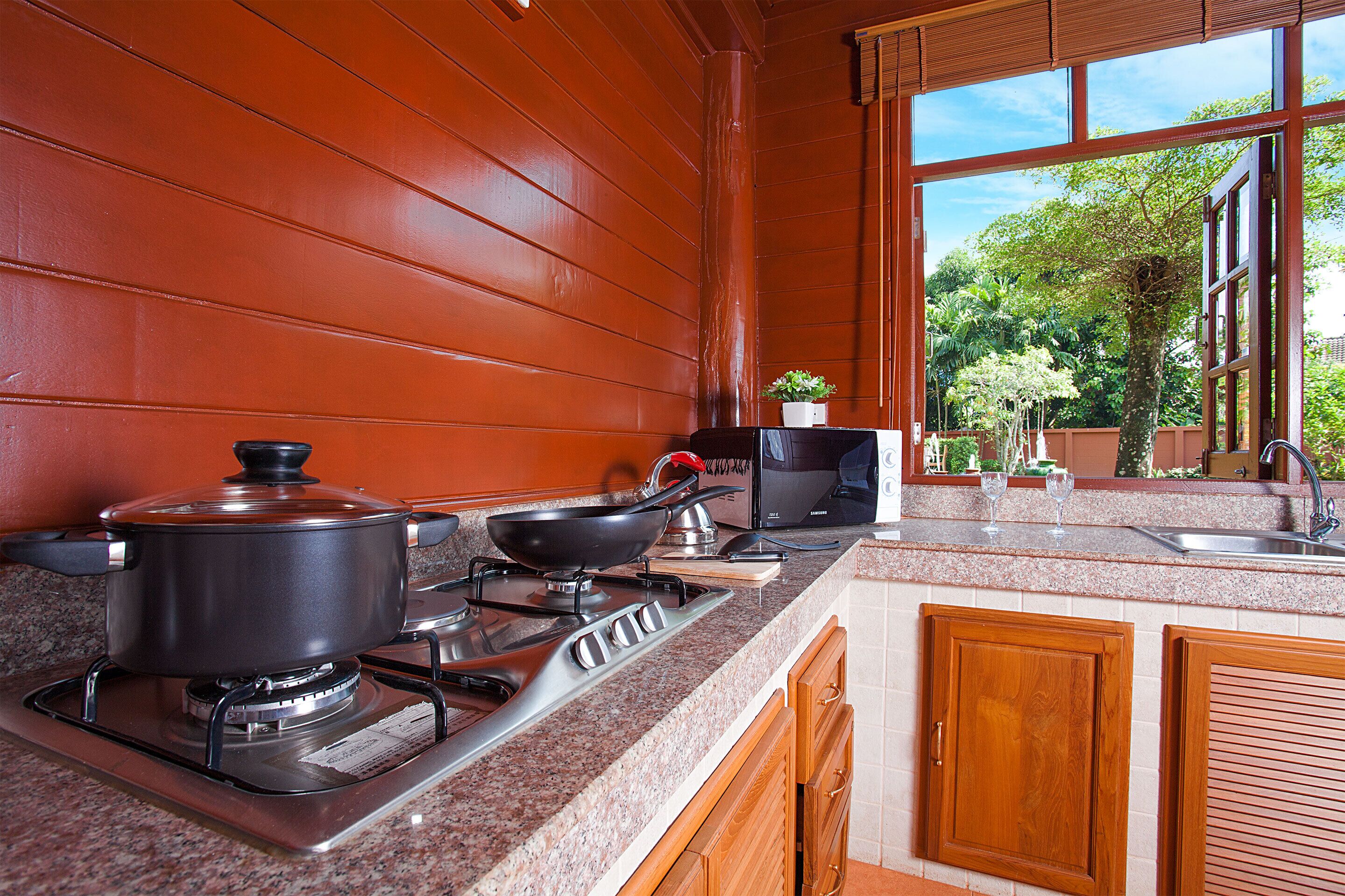 Una cocina con estufa a gas, una olla, una sartén y un microondas.