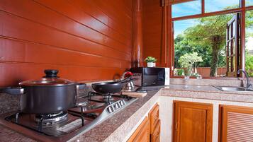 Una cocina con estufa a gas, una olla, una sartén y un microondas.