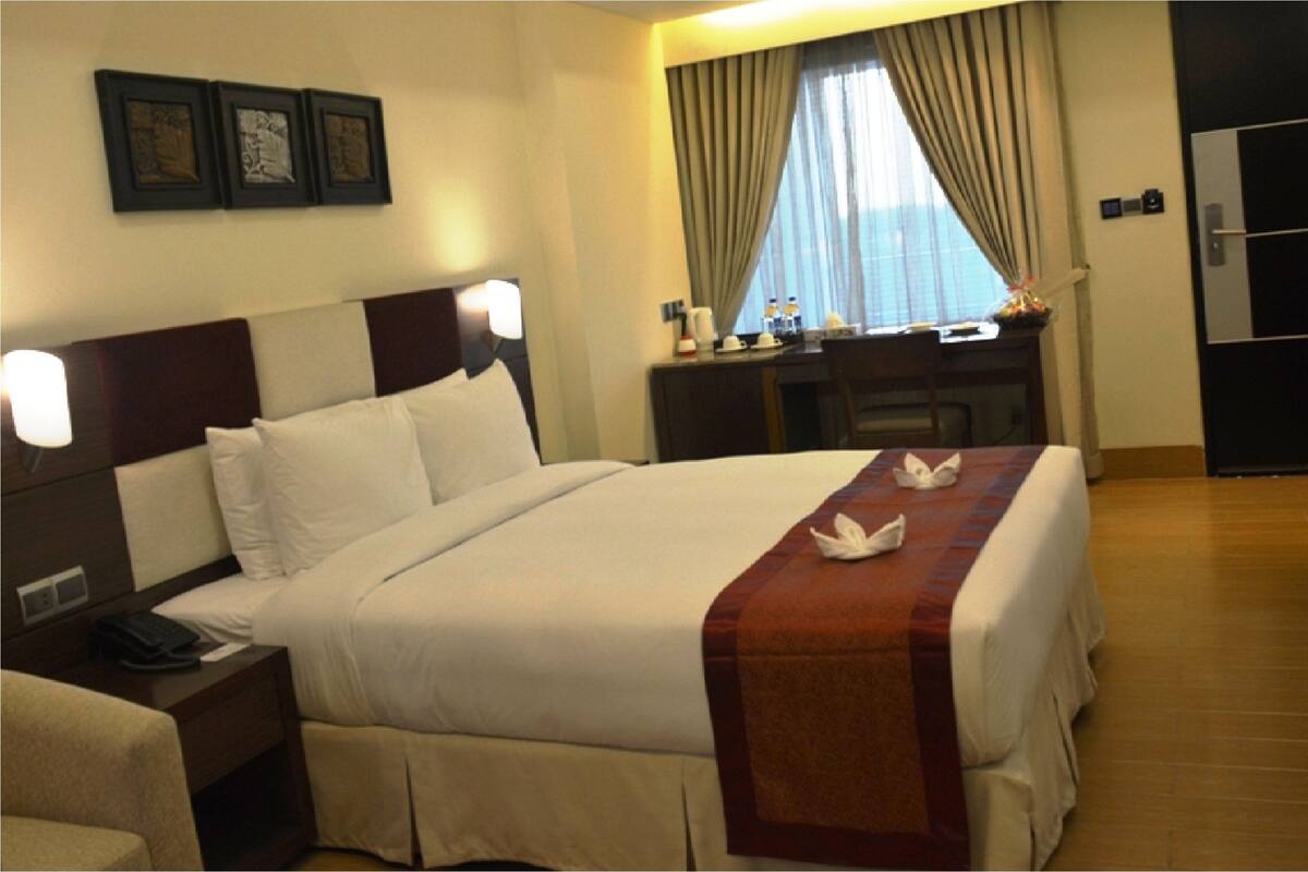 Una habitación de hotel con una cama grande, un escritorio, una silla y un armario.