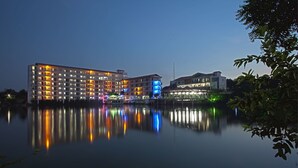 A multi-story hotel with a reflection in the water, featuring a modern architectural design and a calm lake setting. - BRAC-CDM Savar (Savar)