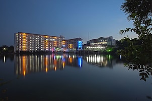 Um hotel de vários andares com reflexo na água, destacando um design arquitetônico moderno e um ambiente tranquilo à beira de um lago.