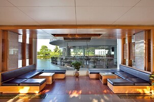 Um lobby moderno com áreas de estar, uma planta central e vista para a área externa.