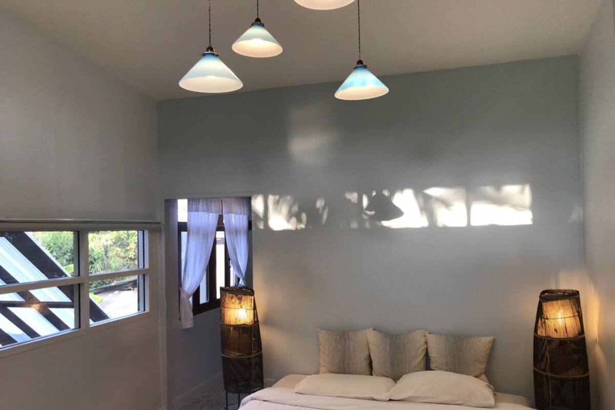 Un dormitorio con cama, lámparas de noche, una ventana y vistas al exterior.