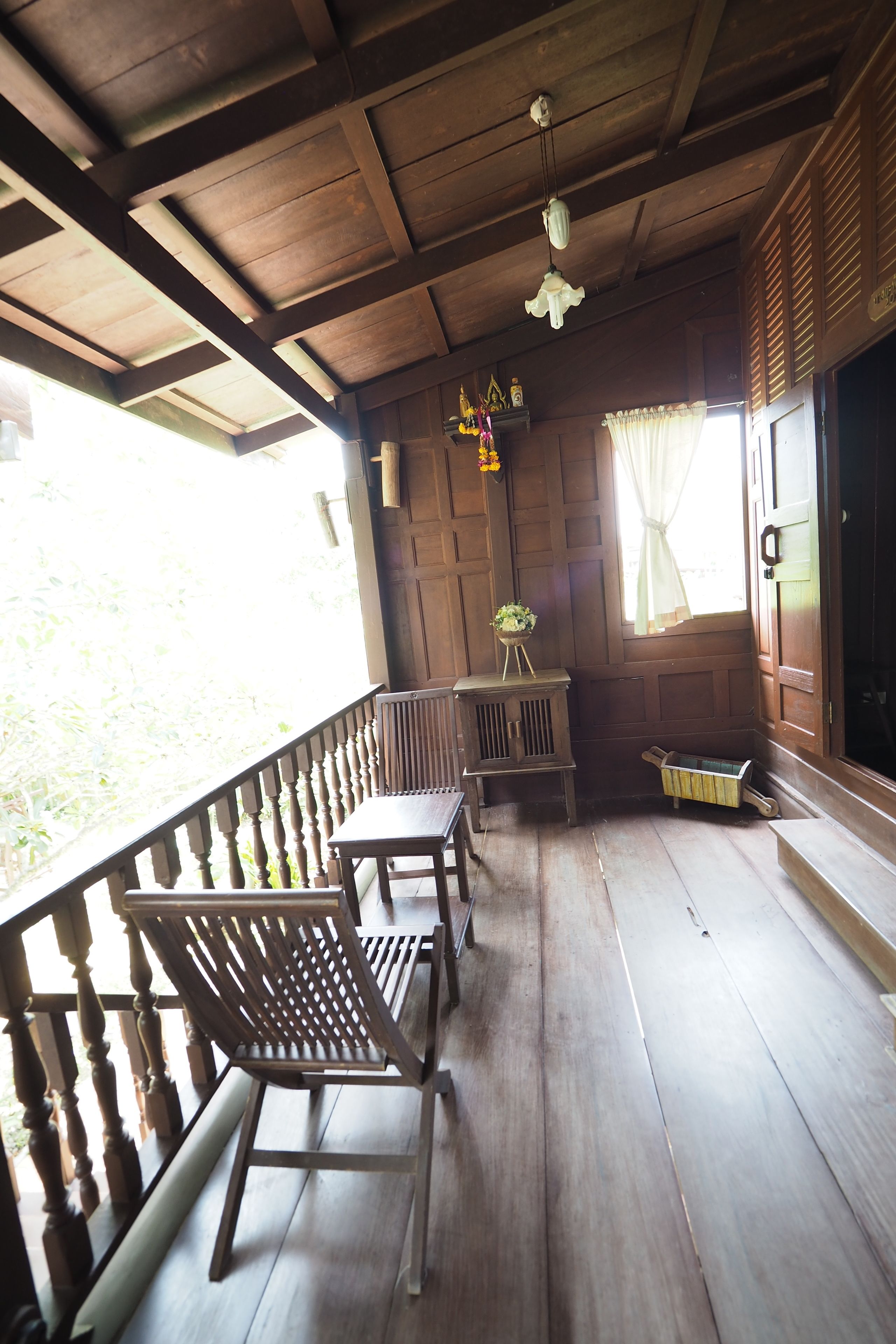 A wooden porch with a bench, a small table, and a potted plant.