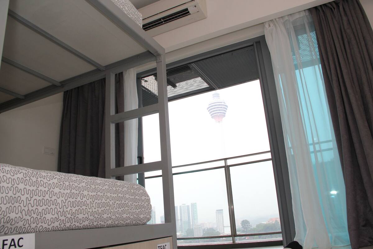 A room with a bunk bed, a window with a view of a cityscape and a hot air balloon, and a ceiling fan.