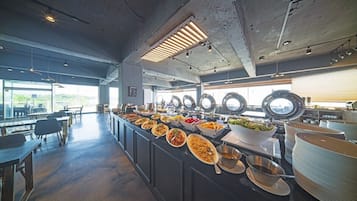 A buffet setup with various dishes, a long counter, and seating area with tables and chairs.