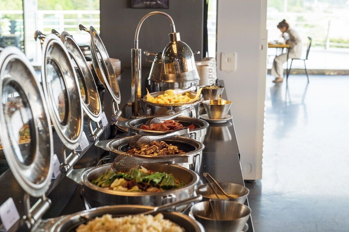 A buffet setup with various dishes and utensils.