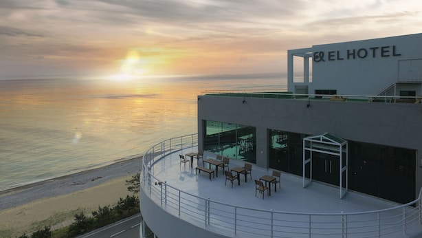 Un hotel con terraza en la azotea y vistas al mar, con asientos al aire libre y una vista despejada del atardecer.