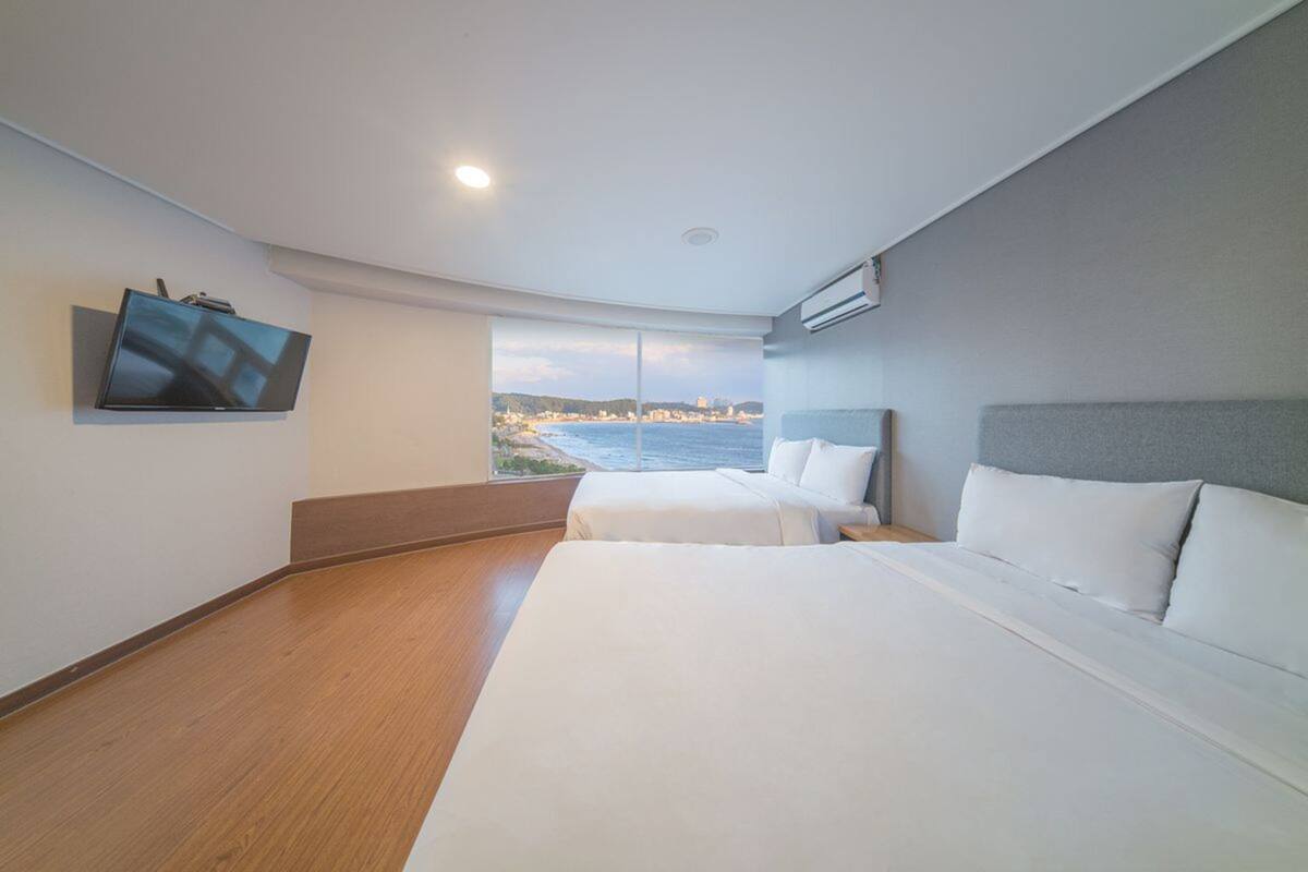 Une chambre d’hôtel avec deux lits, une télévision et vue sur la mer.