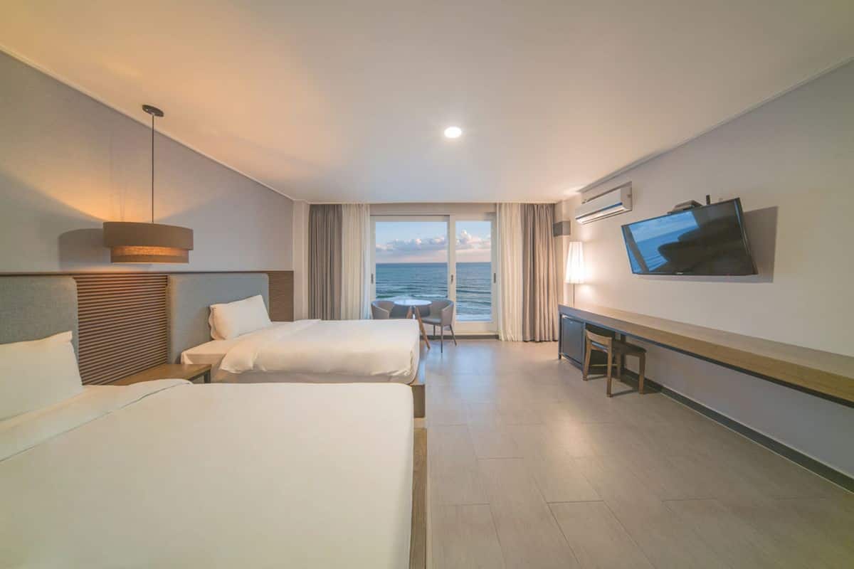 Une chambre d’hôtel avec deux lits, une télévision, un bureau et vue sur la mer.