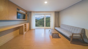 Amplia sala de estar con un banco de madera, un sofá y un televisor sobre un mueble de madera.