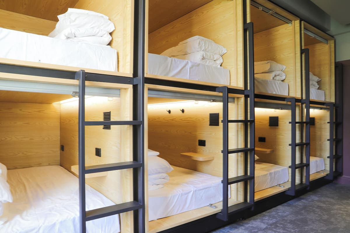 A bunk bed room with wooden frames and white bedding.