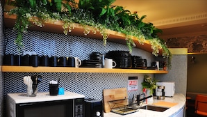 A kitchen with a microwave, coffee maker, and a sign instructing to wash dishes. - The Capsule Hotel - Hostel (Haymarket)