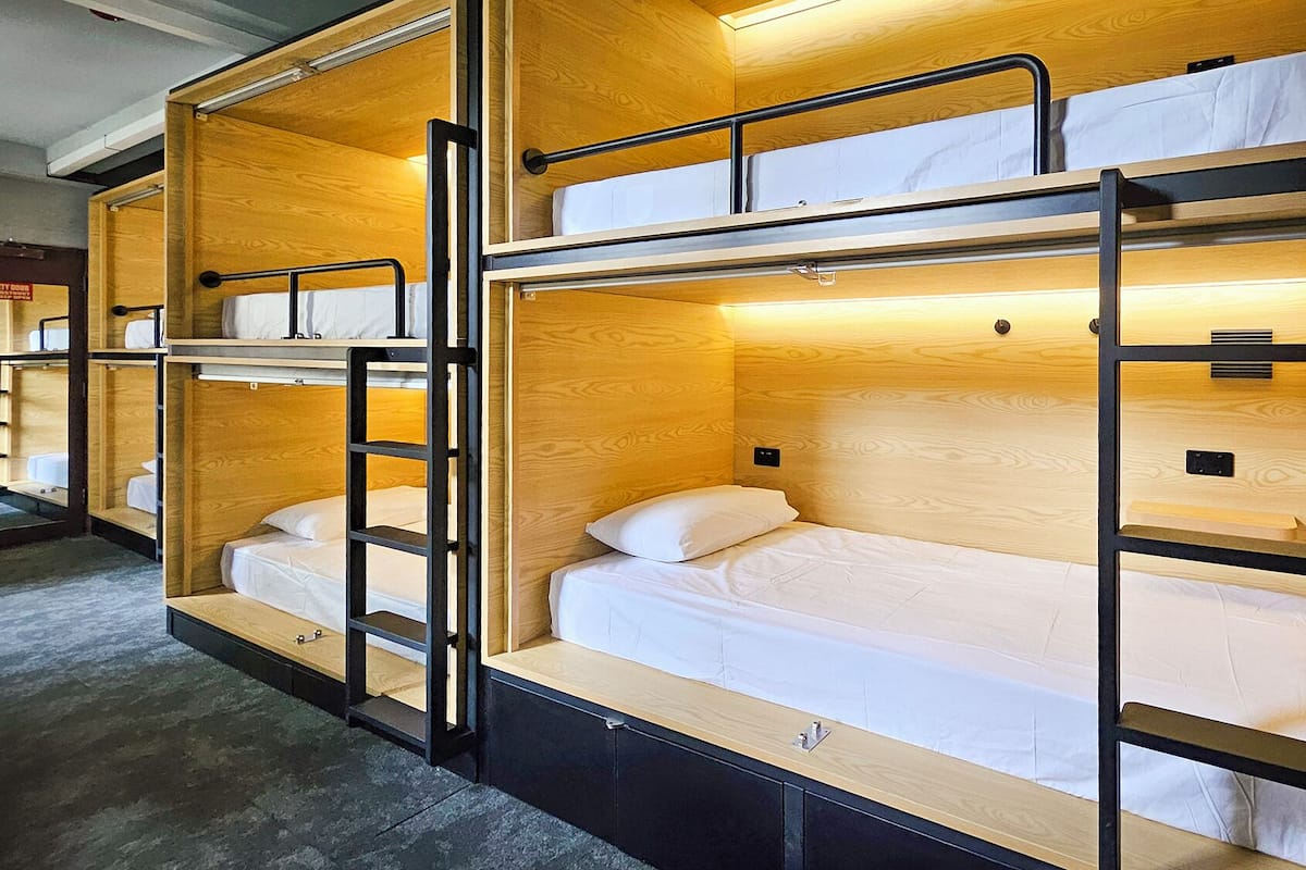 A row of bunk beds with wooden frames and white bedding.