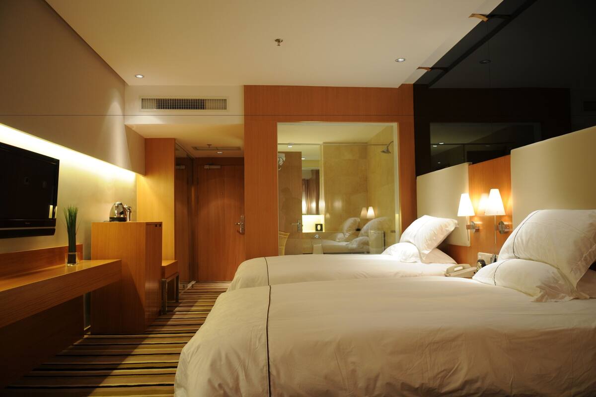 A hotel room with a large bed, bedside lamps, a TV, and a wooden desk.