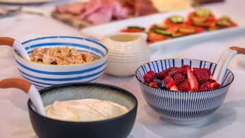 Una mesa con diferentes alimentos, como tazones de yogur, granola y frutos rojos frescos.