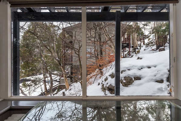 Una ventana con vista a un paisaje nevado, que incluye árboles y un edificio.