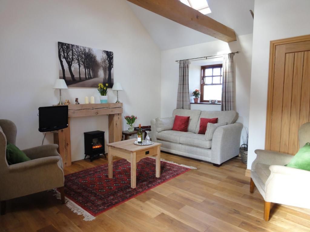 A living room with a sofa, chairs, a coffee table, a fireplace, and a television.