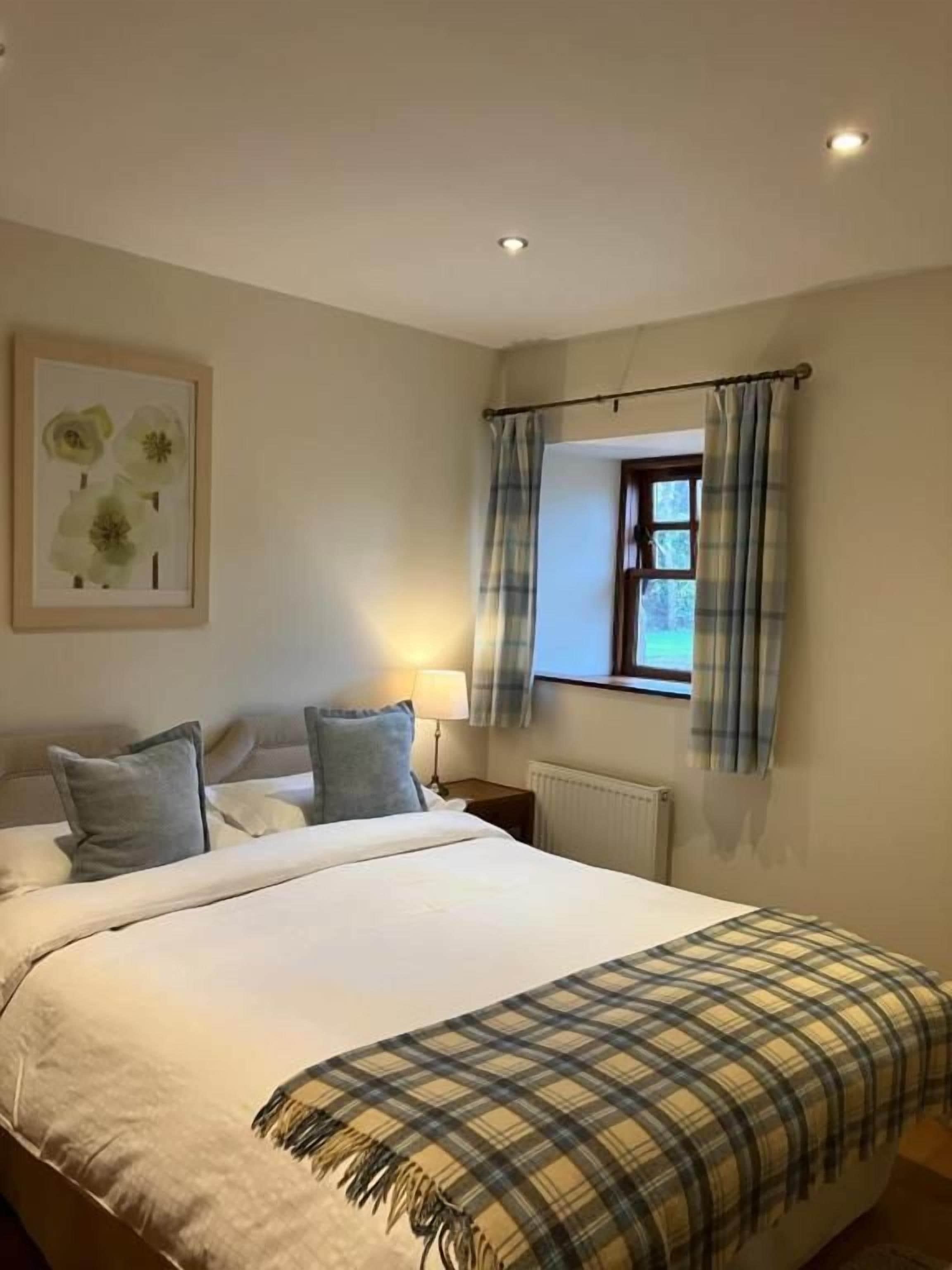 A bedroom with a bed, a window with curtains, a radiator, and a wall-mounted picture.