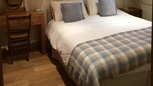 A bedroom with a bed, a desk, a chair, a mirror, a framed picture on the wall, and a window with curtains. - The Courtyard (Perth)