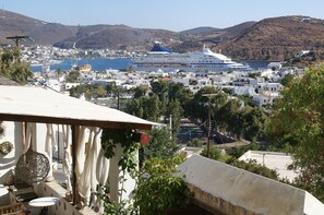 Un pueblo costero con un gran crucero amarrado, edificios blancos y montañas al fondo.