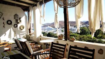 Una terraza con muebles de madera, un farol colgante y vistas a un pueblo costero.