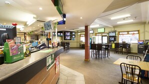 A spacious restaurant with multiple tables and chairs, a counter with a cash register, and several televisions mounted on the walls. - Nightcap at Hume Hotel (Yagoona)
